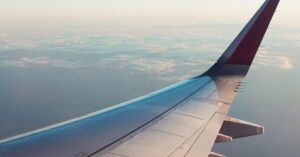 A breathtaking view from an airplane window showcasing clouds and a wing tip over a serene sky.