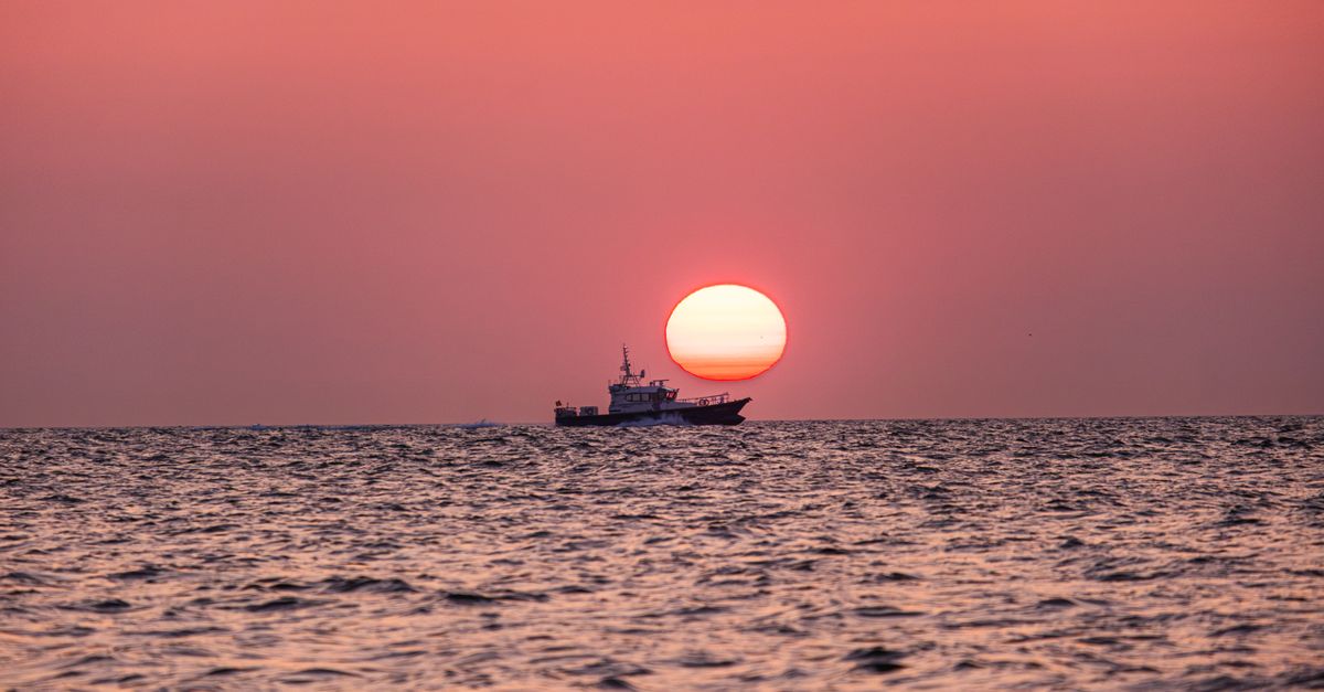 Serene sunset over the ocean with a ship in Middelkerke, Flanders, Belgium.