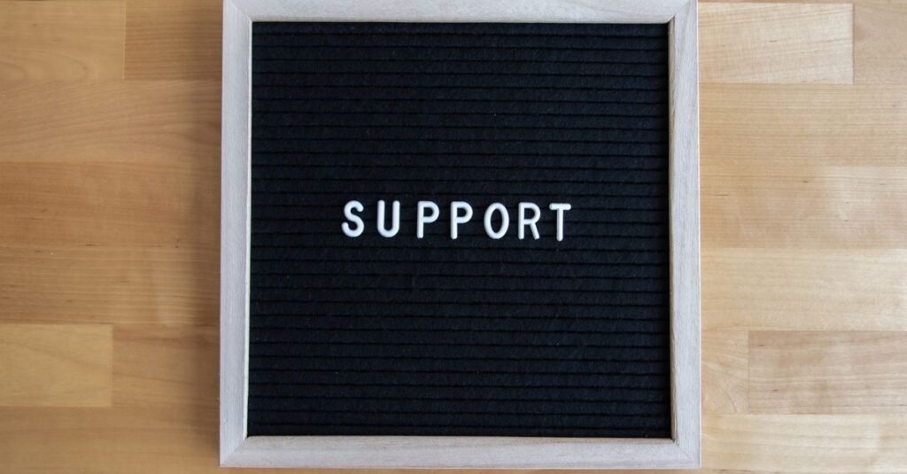 Black letter board displaying the word SUPPORT on a wooden table, offering ample copyspace.
